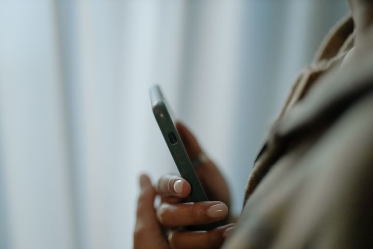 Wanita merenung sambil menatap layar ponsel